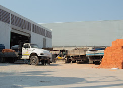 Área externa da loja com caminhões e materiais de construção